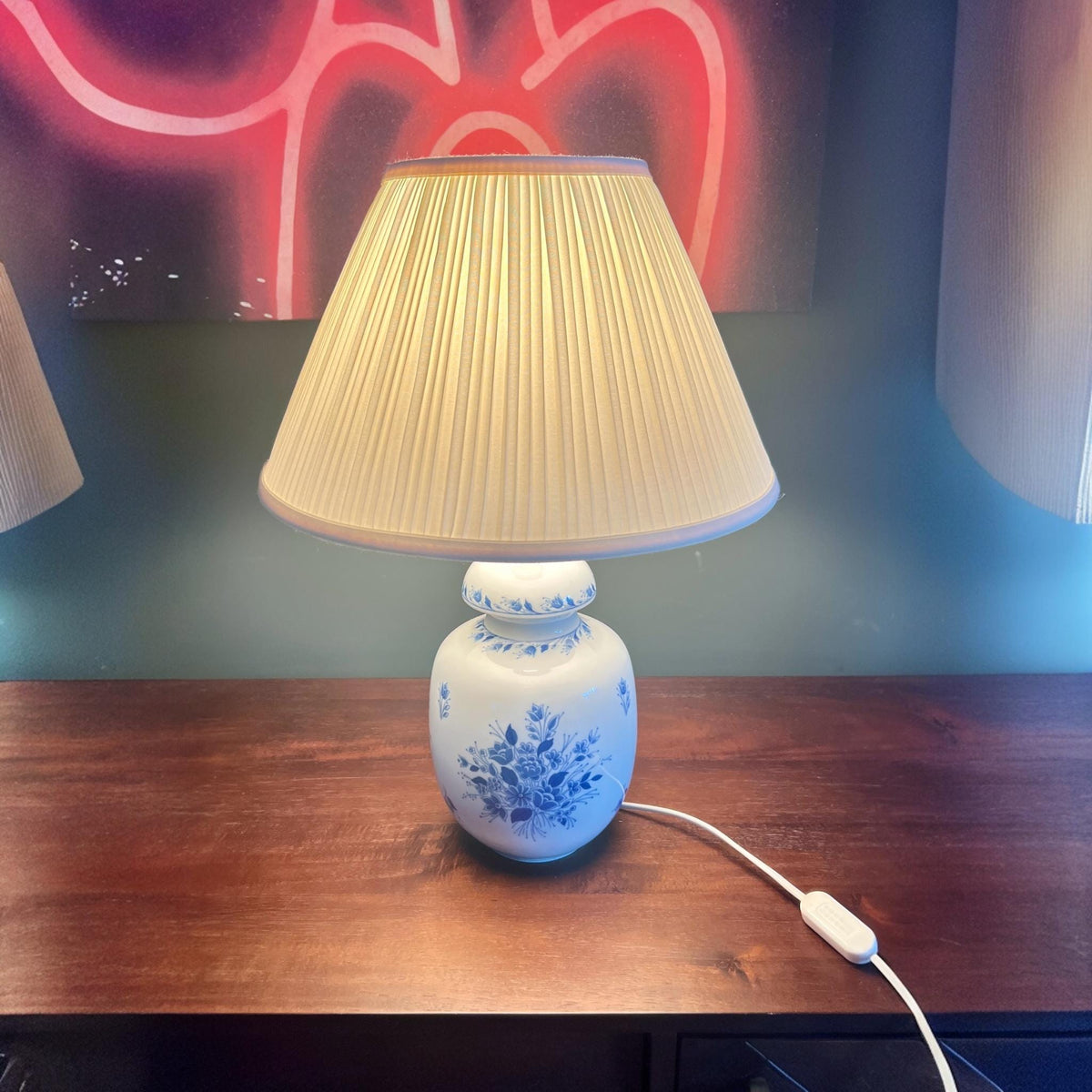 Griechische Mid Century Pegasos Hellas Porzellan Tischlampe mit Plissee-Schirm. Der Porzellanfuß zeigt ein graziles blaues Blumendekor.